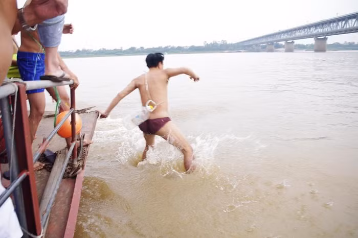 Những ai yếu tim có lẽ không dám lội xuống dòng sông Hồng đỏ nặng phù xa với phao là... can dầu như thế này