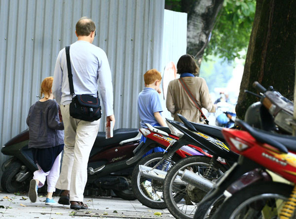 Một gia đình khách nước ngoài len lỏi qua bãi gửi xe lộn xộn