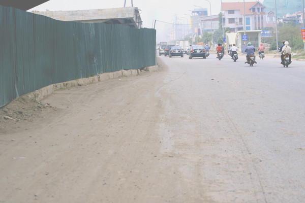 Những lớp bụi đất dày rơi vãi do xe tải chở đất đá đi qua để lại Những lớp bụi đất dày rơi vãi do xe tải chở đất đá đi qua để lại