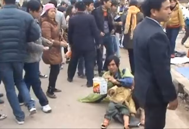Cái bang này mang trên mình trang phục rách tươm và "đèo bòng" thêm một cháu bé. Đứng bên cạnh người phụ nữ mặc áo nâu, đội mũ lưỡi trai hồng là bảo kê cho ăn mày này...