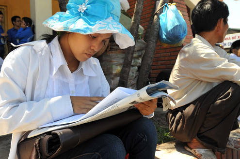 Sau đợt tuyển sinh đầu tiên, một thí sinh thi vào ĐH Thương mại xem gợi ý lời giải, trong khi đợi bắt xe về quê. Thí sinh thi vào ĐH Thương mại xem gợi ý lời giải môn Vật lý. Ảnh: Hoàng Hà.