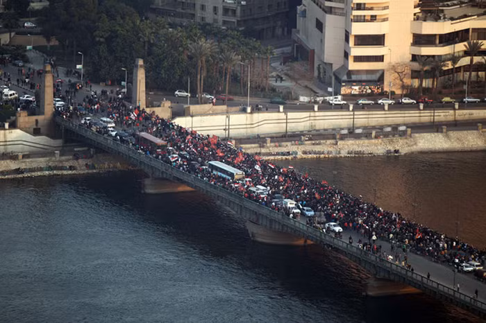 Góc nhìn từ xa cảnh đoàn biểu tình tiến đi trên cây cầu mùng 6/10, ngày lễ kỷ niệm của Lực lượng vũ trang Ai Cập. Trớ trêu thay khi gần 10.000 người đang biểu tình phản đối những người thực hiện nhiệm vụ giữ gìn trật tự trị an.