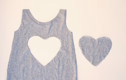 Cắt hình trái tim ở phần thân trước của chiếc áo. Kích thước trái tim lớn hay nhỏ tùy thuộc vào chiếc áo bạn cắt cho hợp lý. Để cắt trái tim cho đẹp, bạn nên cắt trái tim trên giấy làm mẫu sau đó mới cắt trên vải.