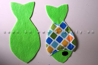 Đặt phần vải hoa văn hình thân cá lên phần vải một màu hình con cá, may gắn chúng với nhau tại đường mang cá. Dùng phần bông dính của đoạn băng dán dính, cắt hình tròn làm mắt cá rồi dán keo hoặc khâu đính vào đầu cá. Mỗi con cá có hai mặt thân, một mặt 1 màu và 1 mặt được trang trí bằng vải có hoa văn. Cầu kỳ hơn, bạn có thể làm mai mặt thân giống nhau, chỉ cần cắt thêm miếng thân cá và trang trí hai bên như nhau là được. Đặt phần vải hoa văn hình thân cá lên phần vải một màu hình con cá, may gắn chúng với nhau tại đường mang cá. Dùng phần bông dính của đoạn băng dán dính, cắt hình tròn làm mắt cá rồi dán keo hoặc khâu đính vào đầu cá. Mỗi con cá có hai mặt thân, một mặt 1 màu và 1 mặt được trang trí bằng vải có hoa văn. Cầu kỳ hơn, bạn có thể làm mai mặt thân giống nhau, chỉ cần cắt thêm miếng thân cá và trang trí hai bên như nhau là được.