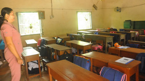 Theo hướng dẫn của cô giáo, học sinh lớp 1 Trường tiểu học Bình Thạnh phải núp dưới gầm bàn mỗi khi trời mưa để được an toàn