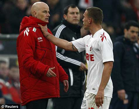 Podolski nắm cổ HLV sau khi bị thẻ đỏ. Ảnh: Reuters