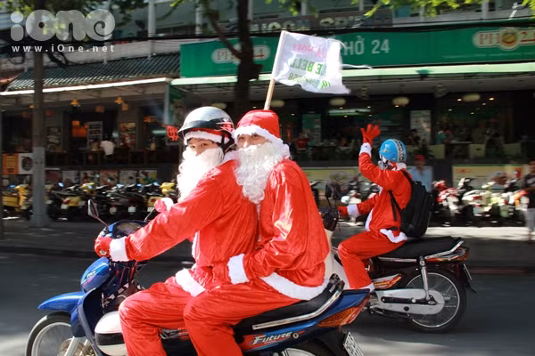 Thay vì cưỡi tuần lộc, các ông già Noel đèo nhau bằng xe máy trong trang phục đỏ rực như thắp lửa các tuyến đường trung tâm TP HCM.