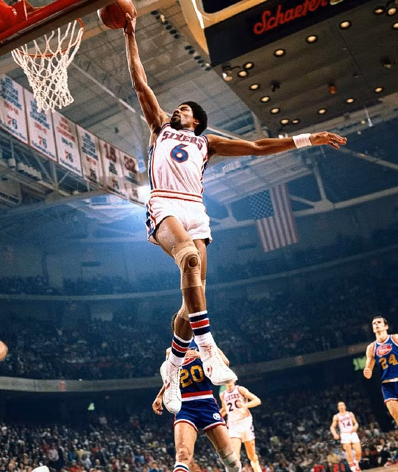 62. Julius Erving: Người ghi điểm nhiều thứ 5 trong lịch sử NBA, “Dr. J” là bệ phóng cho phong cách chơi đề cao những cú dunk trong bóng rổ hiện đại. Erving gây dựng tên tuổi của mình với những cú dunk rất mạnh và quyết liệt cùng những động tác thành công một cách khó tin, trong đó có cú Baseline Lay-up nổi tiếng trong trận chung kết NBA 1980. Erving trở thành người đầu tiên giành chiến thắng tại một Slam Dunk Contest và biến cuộc thi này trở nên nổi tiếng mà sau này trở thành bệ phóng cho “Air Jordan”, tên một thương hiệu giày gắn liền với Michael Jordan. 62. Julius Erving: Người ghi điểm nhiều thứ 5 trong lịch sử NBA, “Dr. J” là bệ phóng cho phong cách chơi đề cao những cú dunk trong bóng rổ hiện đại. Erving gây dựng tên tuổi của mình với những cú dunk rất mạnh và quyết liệt cùng những động tác thành công một cách khó tin, trong đó có cú Baseline Lay-up nổi tiếng trong trận chung kết NBA 1980. Erving trở thành người đầu tiên giành chiến thắng tại một Slam Dunk Contest và biến cuộc thi này trở nên nổi tiếng mà sau này trở thành bệ phóng cho “Air Jordan”, tên một thương hiệu giày gắn liền với Michael Jordan.