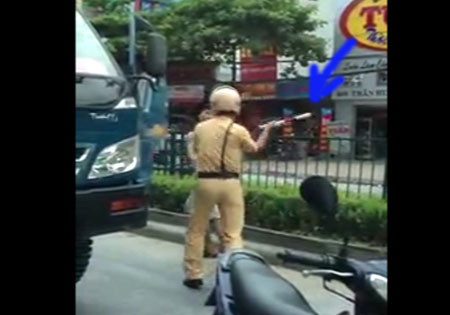 Dùng dùi cui vụt thẳng tay vào mặt lái xe. (ảnh cắt từ video) Dùng dùi cui vụt thẳng tay vào mặt lái xe. (ảnh cắt từ video)