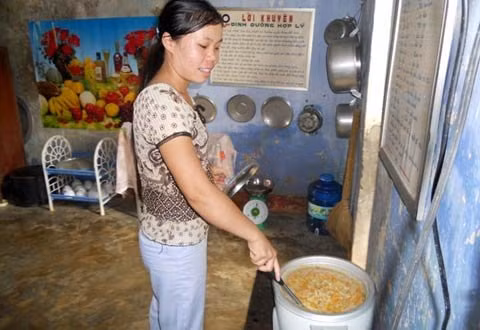 Cô Phạm Thị Thảo đang lo nồi cháo bữa chiều cho các cháu xong đã rồi các cô mới ăn cơm trưa. Ảnh Trần Văn.