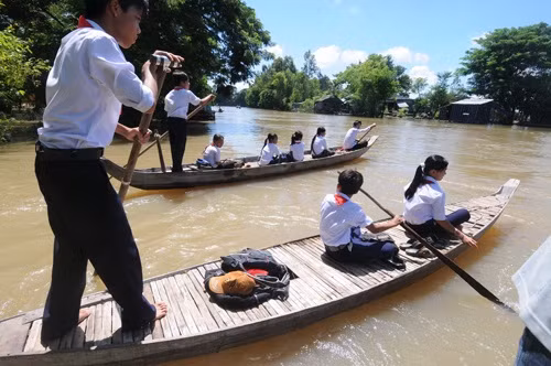 Tại huyện đầu nguồn lũ An Phú (An Giang), ngày khai giảng ở ba xã giáp biên giới với nước bạn Campuchia có trên 900 học sinh là con em Việt kiều đi xuồng, đò để đến trường. Ảnh: Tuổi Trẻ