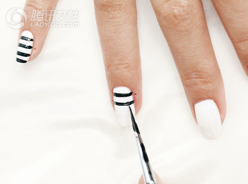 Sau đó dùng bút kẻ móng vẽ những đường sọc ngang lên lớp sơn màu trắng.