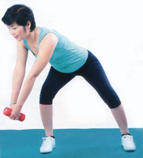 Động tác 7: - Đứng thẳng, hai chân mở rộng bằng vai, hai tay nắm thân tạ, đưa thẳng về trước. - Mắt hướng xuống sàn. Đứng bật dậy, thót bụng, nâng tạ lên cao, lần lượt quay qua trái, phải, rồi trở về tư thế ban đầu. Đổi bên. Lặp lại 10 lần. Chúc bạn thành công!