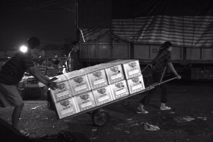 Cứ sau 12 giờ đêm, khu chợ kéo dài liên tục trong bến xe ra đến khu ngoài khu gầm cầu Long Biên lại nhộn nhịp kẻ mua người bán với những thùng hàng rau, quả, củ, dỡ xuống từ những chiếc xe tải đến từ khắp nơi.