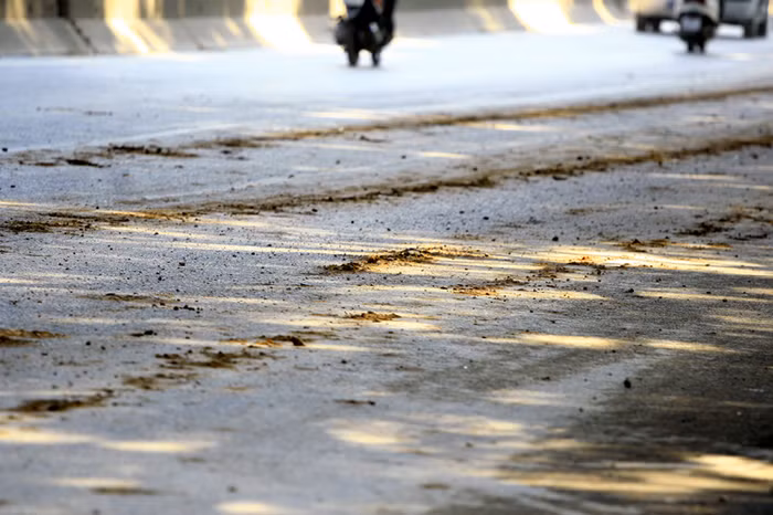 Mặt đường Phạm Văn Đồng nhiều đoạn vương vãi đất cát do xe tải chở đất, cát để lại sau mỗi lần rơi vãi