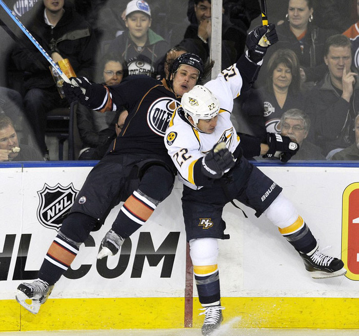 Ryan Jones (trái) của Edmonton Oilers và Jordin Tootoo của Nashville Predators va chạm với nhau ngay trước hàng ghế khán giả trong một trận đấu hockey