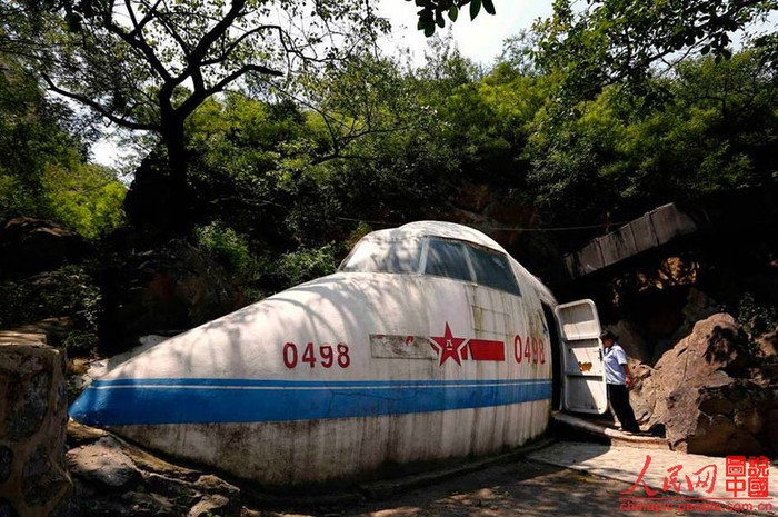 Cổng vào của quán bar có một không hai này là phần đầu của chiếc máy bay mang số hiệu “0498”. Đây cũng chính là tên gọi của quán bar đặc biệt này. Cánh cửa của máy bay cũng chính là lối vào của các công sự ngầm.