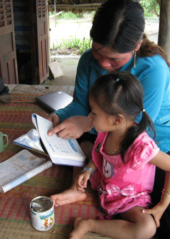 Mẹ đang chỉ bé đọc sách.