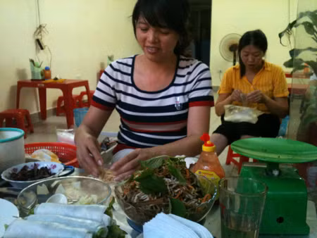 Dùng tay trần cuốn nem, phở cho khách, chốc chốc chị lại nhận tiền, trả tiền thừa cho khách rồi lại tiếp tục cuốn nem Ảnh Dan tri.