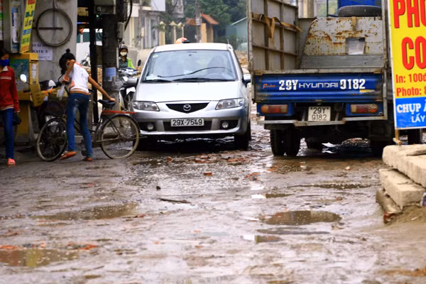 Hai chiếc ô tô chen chúc nhích từng tý mới qua được vì quá nhiều ổ gà, ổ trâu