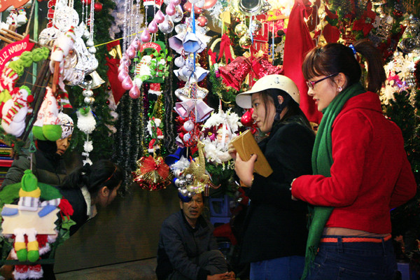 Màu đỏ của những bộ đồ Noel, tất, mũ Noel, các hình ông già Tuyết, quả cầu, quả châu trang trí hay màu xanh, màu bạc của những cây thông Noel, quả chuông, dây kim tuyến…là những sắc màu của những con phố quà tặng nổi tiếng Hà Nội những ngày này. Màu đỏ của những bộ đồ Noel, tất, mũ Noel, các hình ông già Tuyết, quả cầu, quả châu trang trí hay màu xanh, màu bạc của những cây thông Noel, quả chuông, dây kim tuyến…là những sắc màu của những con phố quà tặng nổi tiếng Hà Nội những ngày này.