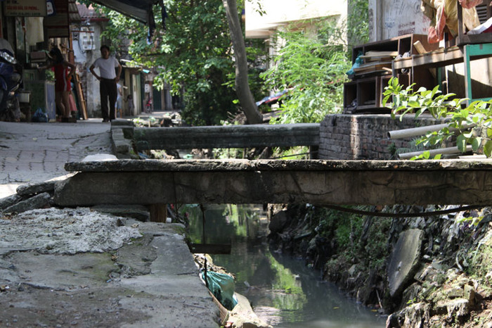 Những chiếc cầu tạm bợ bắc qua con mương đen này được người dân dựng lên để đi tạm trong khi "đợi chờ trong mỏi mòn" dự án cải tạo con mương đen này được thực hiện. Những chiếc cầu tạm bợ bắc qua con mương đen này được người dân dựng lên để đi tạm trong khi "đợi chờ trong mỏi mòn" dự án cải tạo con mương đen này được thực hiện.