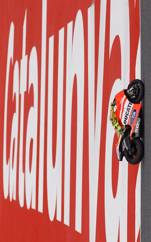 Valentino Rossi đi qua một tấm biển lớn đề Catalunya