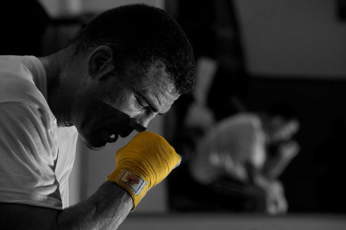 Tay đấm Jorge Sendra ngồi lặng lẽ sau một trận đấu quyền anh. Ảnh chụp nền đen - trắng với chiếc găng tay màu vàng