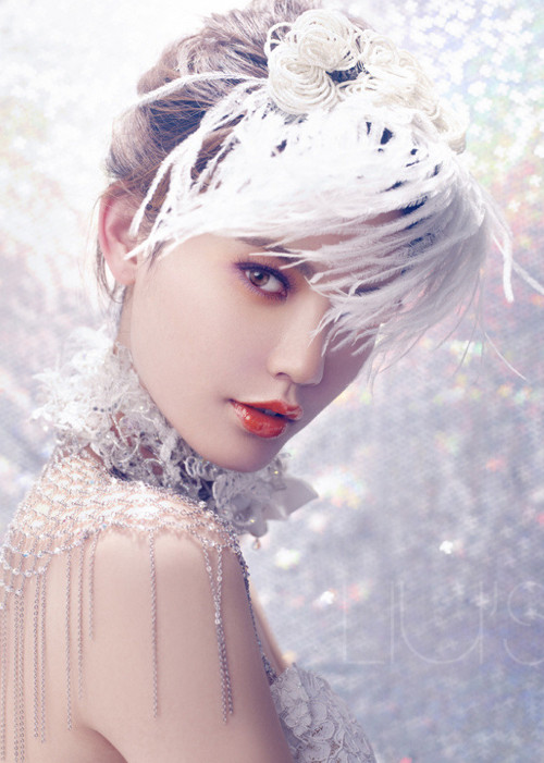 Tông son cam tươi trẻ kết cùng với phấn mắt tím phớt là gợi ý mới lạ. Trong khi đó, phần tóc được vấn đơn giản kết hợp với lông vũ để tăng vẻ sang trọng.