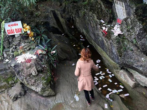 Một thiếu nữ rắc tiền xuống dưới "Suối giải oan" để cầu may. Một thiếu nữ rắc tiền xuống dưới "Suối giải oan" để cầu may.