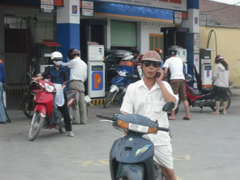 Vô tư đứng trước ống kính máy ảnh nghe điện thoại bên cây xăng