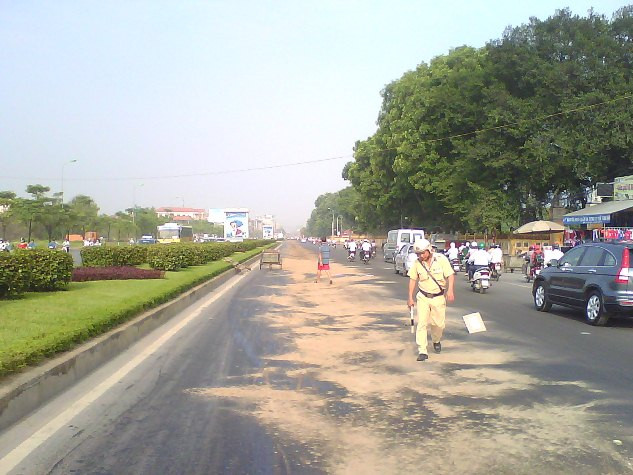 Một chiến sỹ CSGT gạt cát ra vết dầu loang.