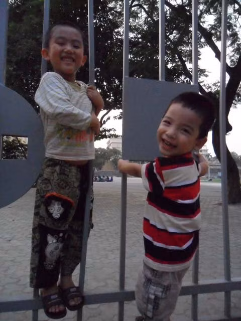 Hai đứa trẻ hân hoan chơi trò đu cổng và “chui ra chui vào”.