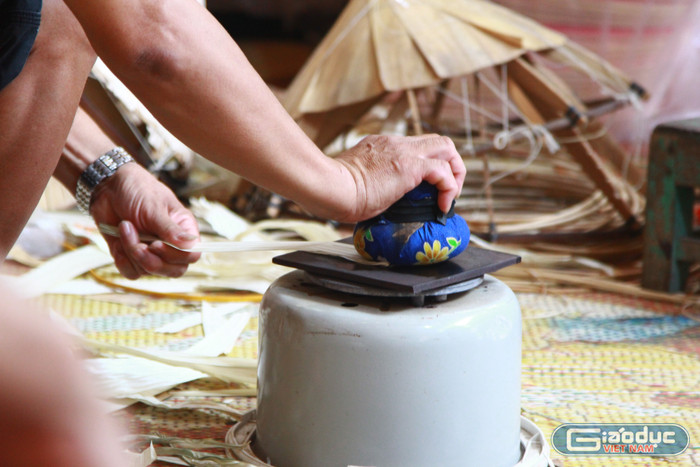 Nghệ nhân Tuy thực hiện công đoạn là lá cọ non để chiếc lá được phẳng. Công đoạn này là từ một bó vải được buộc chặt là chiếc lá trên một tấm kim loại được làm nóng. Ảnh: Mạnh Đoàn gdvn-nghe-nhan-lang-chuong-lam-non-le-van-tuy-8.jpg