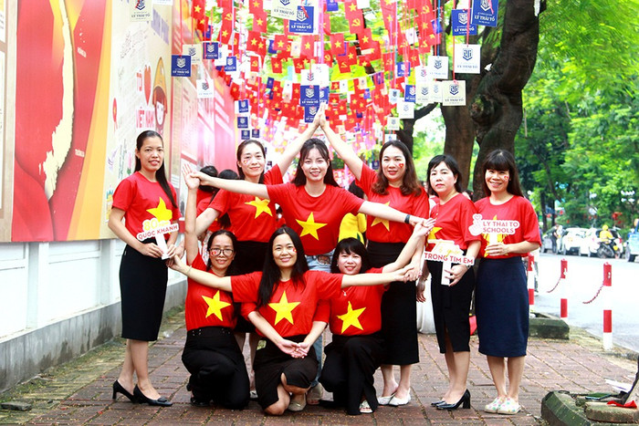 Sau khi kết thúc chương trình, đội ngũ giáo viên Hệ thống Lý Thái Tổ đã đến khu vực ngoài trường được trang trí pano, áp phích, cờ... rực rỡ sắc màu của Tổ quốc để chụp hình kỷ niệm. Trong ảnh, các nữ giáo viên tạo hình ngôi sao 5 cánh. he-thong-giao-duc-ly-thai-to-6.jpg