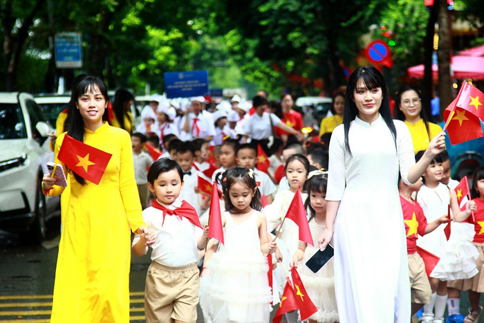 Hai nữ giáo viên dắt các học sinh Trường mầm non Lý Thái Tổ tham gia diễu hành. he-thong-giao-duc-ly-thai-to-3.jpg