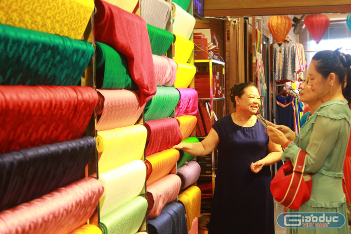 Bà Nguyễn Thị Tâm giới thiệu cho khách hàng về mẫu vải lụa làm bằng 100% tơ tằm với giá thành khá cao. Bên cạnh đó, cơ sở cũng có những mẫu vải tơ tằm chiếm 70% sẽ có giá thấp hơn. Tất cả sản phẩm được công khai về giá cả và chất liệu. gdvn-lang-lua-van-phuc-ha-dong-4.jpg