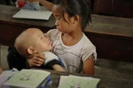 Rưng rưng ảnh bé gái lớp 2 ẵm em vào lớp học