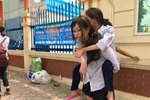 Nữ sinh cõng bạn trên lưng đứng đợi người thân