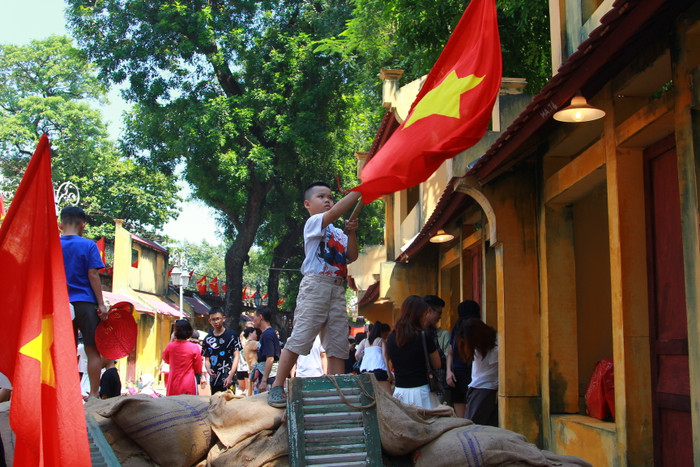 Một cháu bé vẫy cờ tái hiện khung cảnh người dân chào đón bộ đội về tiếp quản Thủ đô. (Ảnh: Mạnh Đoàn) IMG_0725.JPG