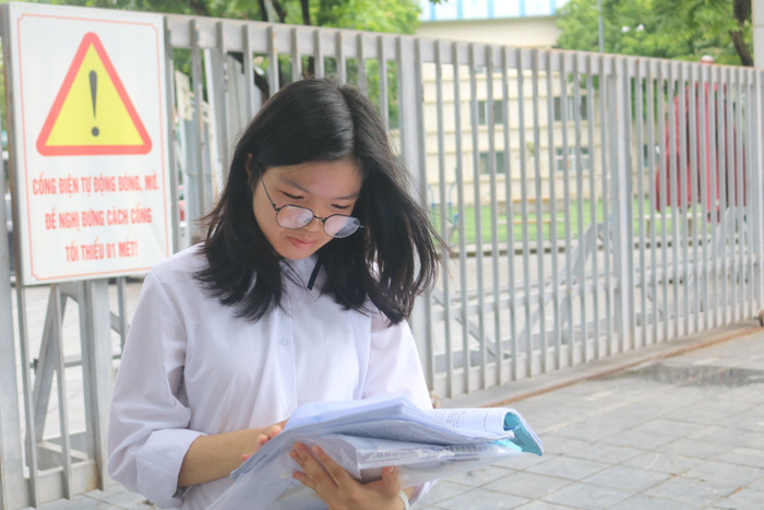 Học sinh Lê Bảo Vy tranh thủ ôn lại bài tại điểm thi Trường Trung học cơ sở Dịch Vọng. Ảnh: Vân Ánh
