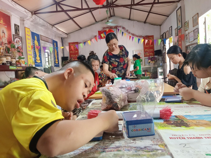 Bà Đoàn Thị Hoa chỉ bảo các em khuyết tật làm nghề. (Ảnh: Mạnh Đoàn)