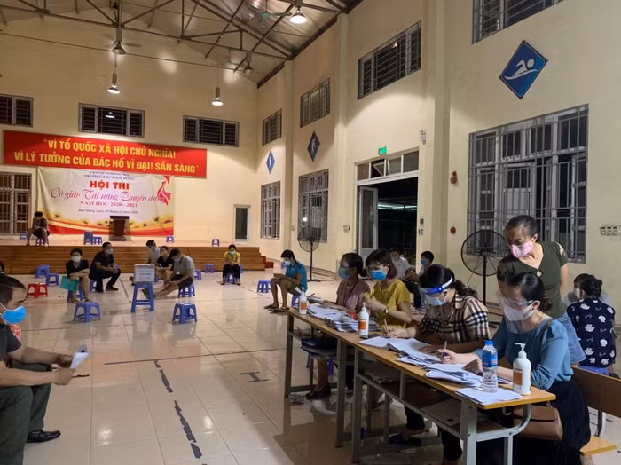 Các giáo viên trong nhà trường tiếp đón người dân đến tiêm vắc xin. (Ảnh: NVCC)