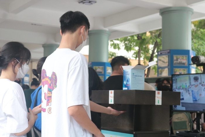 Thí sinh tại điểm trường Trung học cơ sở và Trung học phổ thông Nguyễn Tất Thành tiến hành sát khuẩn tay trước khi vào trường làm thủ tục dự thi. (Ảnh: Doãn Nhàn)