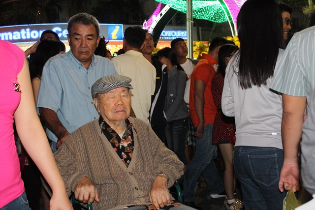 Một cụ già ngồi xe lăn cũng được người thân đưa đến tận hưởng vẻ đẹp đường hoa