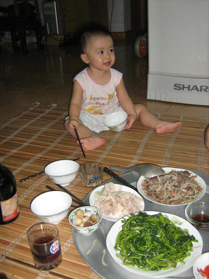 "“Món cà muối và cái nhăn mặt của bố chồng”: Lấy chồng người Bắc, món cà miền Trung trắng tinh, vỏ mỏng, giòn tan là đặc sản trong bữa cơm của gia đình tôi. Nó cũng là món ăn gắn liền với thương hiệu con dâu miền Trung của tôi trong đại gia đình bên chồng. Không trở thành thương hiệu sao được, khi lần đầu tiên về làm dâu, cũng là lần đầu tiên tôi trổ tài món muối cà đặc sản này, đã khiến bố chồng tôi ngạc nhiên. Thay vì hỏi mẹ đẻ, tôi lọ mọ trổ tài món muối cà bằng việc đặt hàng mẹ một kg cà trắng, tròn đều và hăng hái ra chợ mua hẳn 1kg muối. Trong suy nghĩ của tôi, muối cà phải 50-50, 1kg cà phải 1kg muối. Thế mới giòn, mới trắng, mới để lâu được. Cà phơi héo, rửa sạch, tôi xếp cà vào lọ. Một cân muối tôi hòa tan vào nước và đun sôi, để nguội rồi đổ vào lọ cà. Tôi dằn miếng đá cuội to và yên tâm xếp lọ cà vào góc bếp. Quả đúng như dự đoán của tôi, cà trắng phau, đều đặn, trông thật ngon mắt. Một tuần trôi qua, tôi trịnh trọng bưng bát cà muối, xếp cạnh bao món thịt cá khác. Đặc biệt hơn, tôi còn về sớm làm hẳn bát canh cua mồng tơi rau đay có bổ sung thêm bột ngọt chứa vị Umani, ăn với cà miễn chê. Phải nói là bố chồng tôi háo hức biết chừng nào khi cả tuần nay nghe tôi kể về món cà muối miền Trung. Nào là giòn, nào là thơm, nào là trắng. Thế nên, khi vừa ngồi vào mâm, ông vừa xuýt xoa vừa gắp quả cà lên, cho tất vào miệng, nhai ngay. Song, kì lạ thay, ông nhắm mắt nhắm mũi ăn hết quả cà rồi chạy vội ra bình nước, uống hết một cốc to. Mẹ chồng tôi thấy vậy rón rén cắn 1/10 quả cà và nhăn mặt kêu to: Trời ơi, mặn quá! Vậy đấy! Thế là mẻ cà muối đầu tiên của tôi thất bại thảm hại. Trình độ muối cà của tôi về sau có tăng lên chút xíu. Hai nhóc tì của tôi cũng đam mê món cà muối miền Trung này"