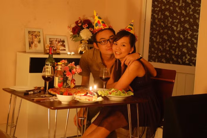 "Tôi và anh xã cưới nhau đã được hơn 9 tháng. Đây là bữa tiệc 2 người ấm cũng tôi dành tặng riêng anh nhân dịp sinh nhật anh, chưa đầy 1 tháng sau lễ cưới. Tôi nghĩ mình cần làm một điều gì đó thật đặc biệt, thật khác với những năm tháng chúng tôi yêu nhau, sinh nhật đầu tiên khi tôi và anh đã là một gia đình thực sự. Tôi bí mật chuẩn bị trong gần một tuần với từng chi tiết nhỏ nhất. Từ nguyên liệu làm bánh, đồ trang trí, nến, hoa và thậm chí là cả dụng cụ khui rượu.Hôm đó, anh đi làm cả ngày và hẹn 6h chiều về nhà mừng sinh nhật cùng nhau. Tôi vui vẻ và hạnh phúc dành cả một buổi chiều để tự tay chế biến bữa tối với Pizza (món ăn ưa thích của anh, rất giàu tinh chất Umami có trong cà chua), salad, rượu và bánh sinh nhật. Tôi cố gắng dành một chút thời gian còn lại trước khi anh xã về để trang trí bàn ăn và nhà cửa. Và bức ảnh này đã ghi dấu lại bữa tối sinh nhật bất ngờ và hạnh phúc của chúng tôi. Nó có thể chưa thực sự hoàn hảo, nhưng tình cảm và niềm vui chúng tôi cùng nhau chia sẻ đã làm bữa tối ấy trở nên trọn vẹn, ý nghĩa hơn, để ghi dấu lại những kỷ niệm đầu tiên khi chúng tôi thực sự là một gia đình :x"