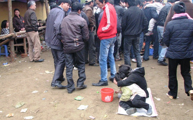 Hai chị em chọn được điểm ngồi nơi đông người qua lại nhất tại lễ hội chọi Trâu Hải Lựu (Vĩnh Phúc) để kiếm ăn (ảnh: Cao Tuân)