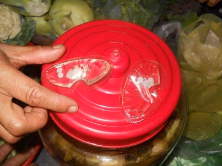 Hai gói dung dịch có chứa 6 viên thuốc nhỏ màu trắng được lấy ra khỏi chiếc ngực trước sự chứng kiến của các tiểu thương trong chợ. (Ảnh: Hồng Sơn)