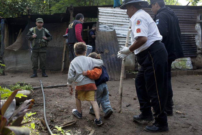 Cậu bé Carlos Daniel Gonzalez 6 tuổi đang ôm em gái Izabel 4 tuổi khi được nhà chức trách đưa ra sau khi các tay súng giấu mặt giết hại bố mẹ và họ hàng các em ở Villa Canales, Guatemala hôm 09/10. Bảy thành viên trong gia đình đã bị sát hại, trong đó có 2 trẻ em. Carlos đã trốn và sống sót sau vụ tấn công.